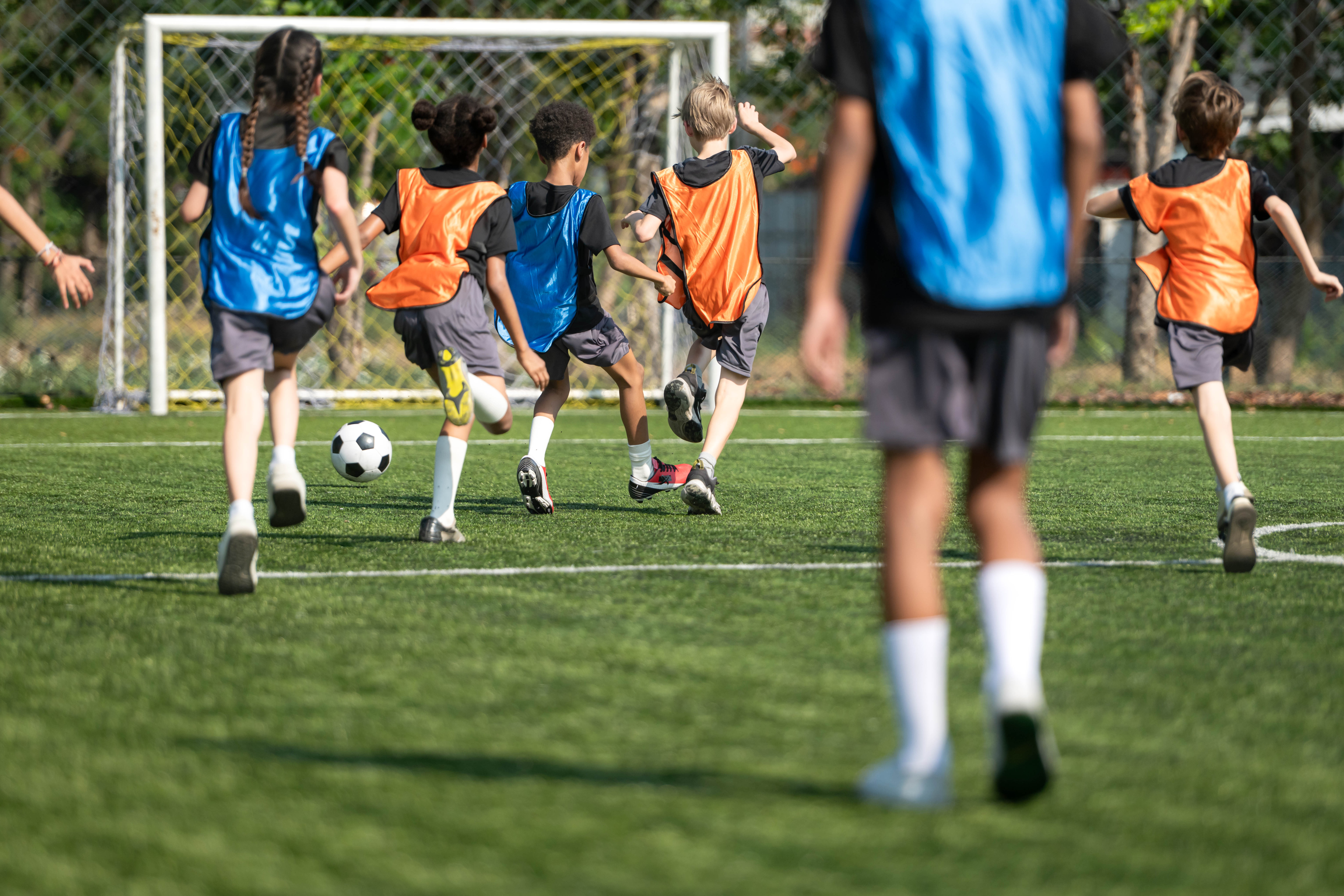 Group of international school kids playing soccer together on the field, showing teamwork, diversity, and active childhood lifestyle