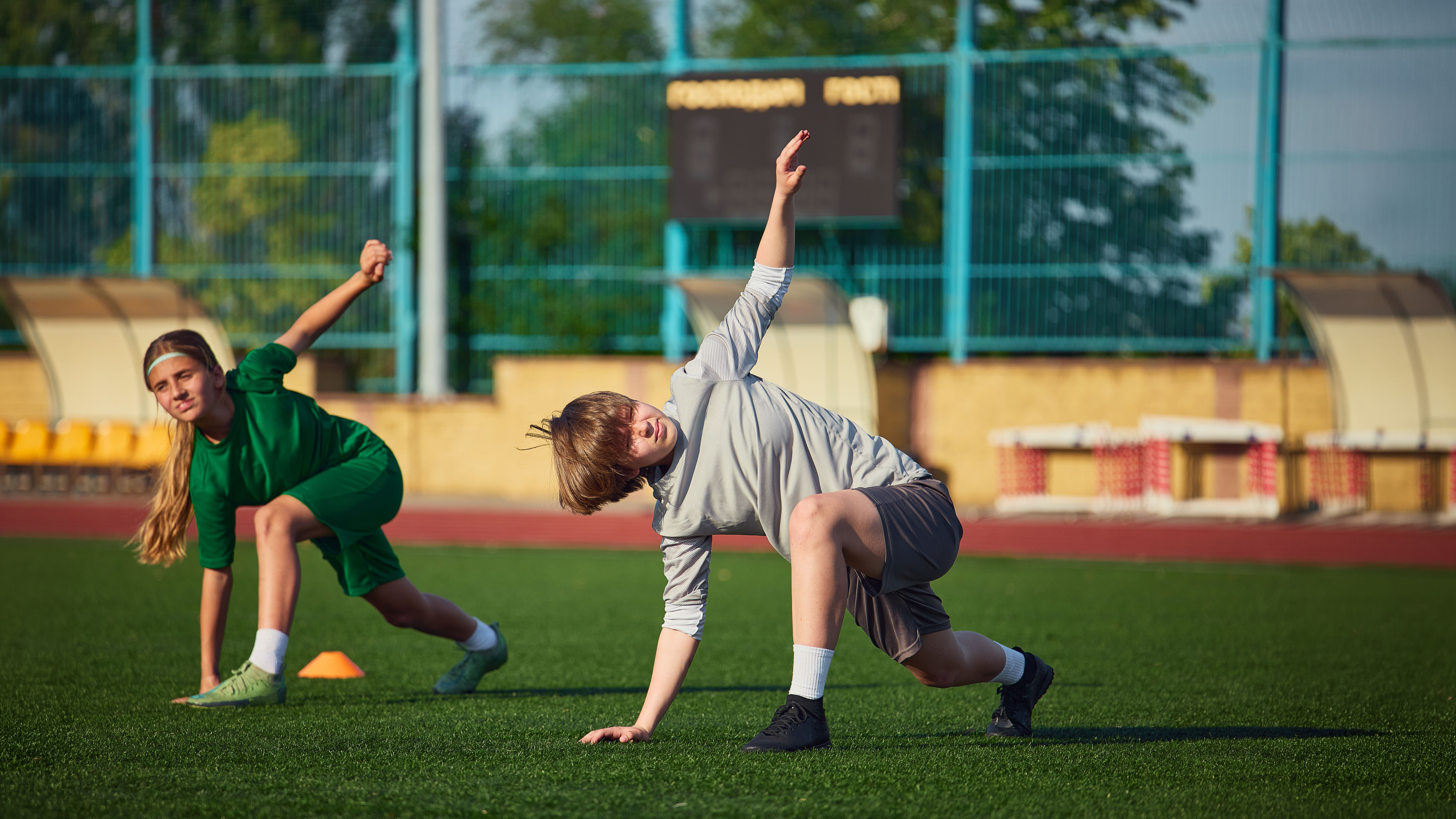 Young soccer players stretching during outdoor academy training. Concept of football academy, healthy lifestyle, youth development, warmup routine and summer sports camp.